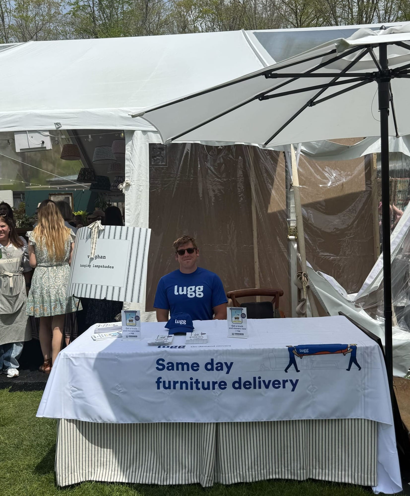 Lugg team member Mac providing same-day delivery support at The Ticking Tent pop-up event, standing by the branded Lugg tent at Spring Hill Vineyards.