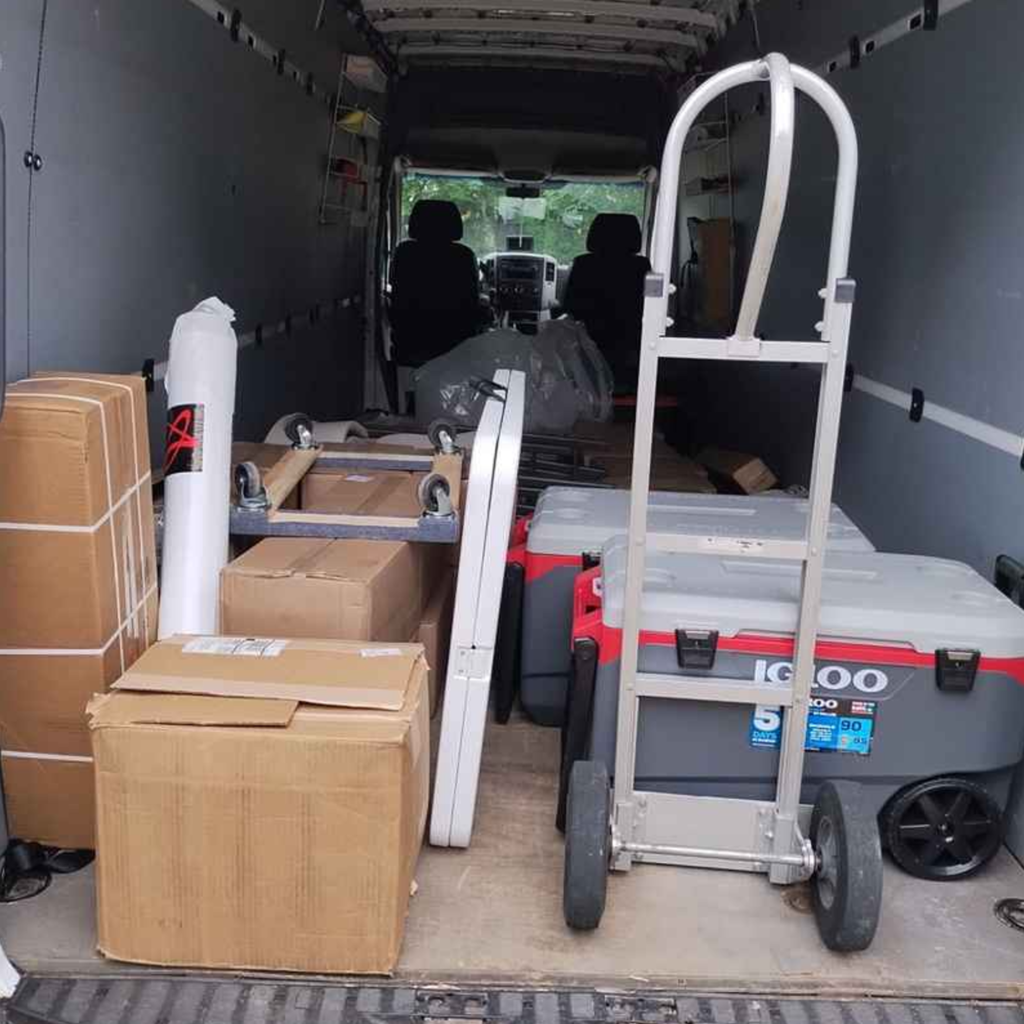 A cooler and several boxes stacked in the back of a moving van, showing tips for keeping perishables fresh during a summer move.