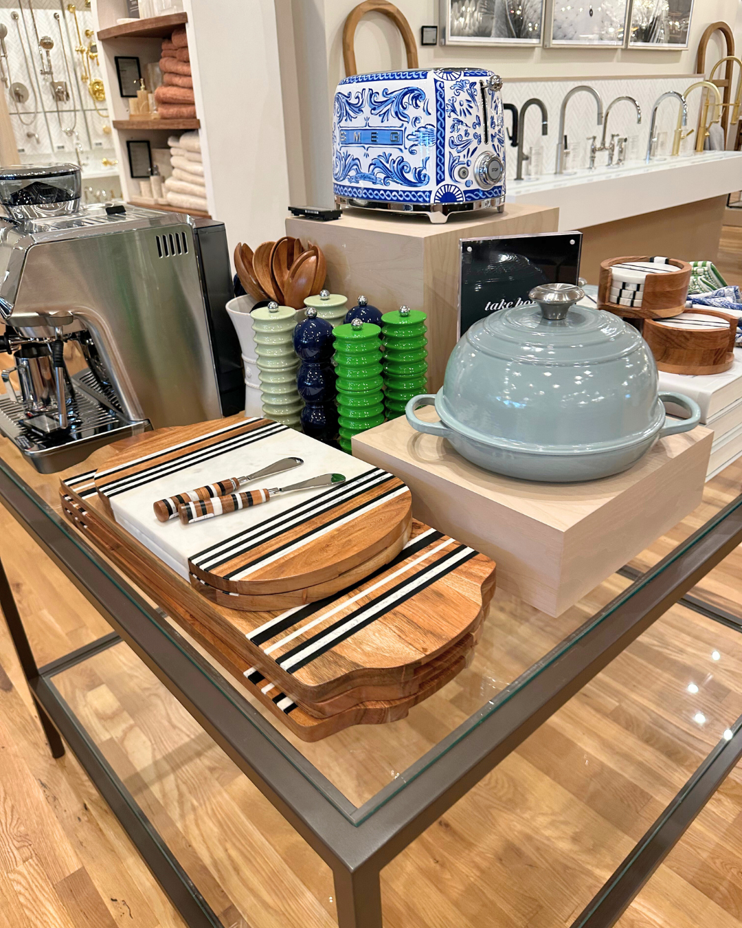 Tabletop display of luxury kitchen accessories at Perigold Houston, including wooden cutting boards, ceramic cookware, and decorative appliances.