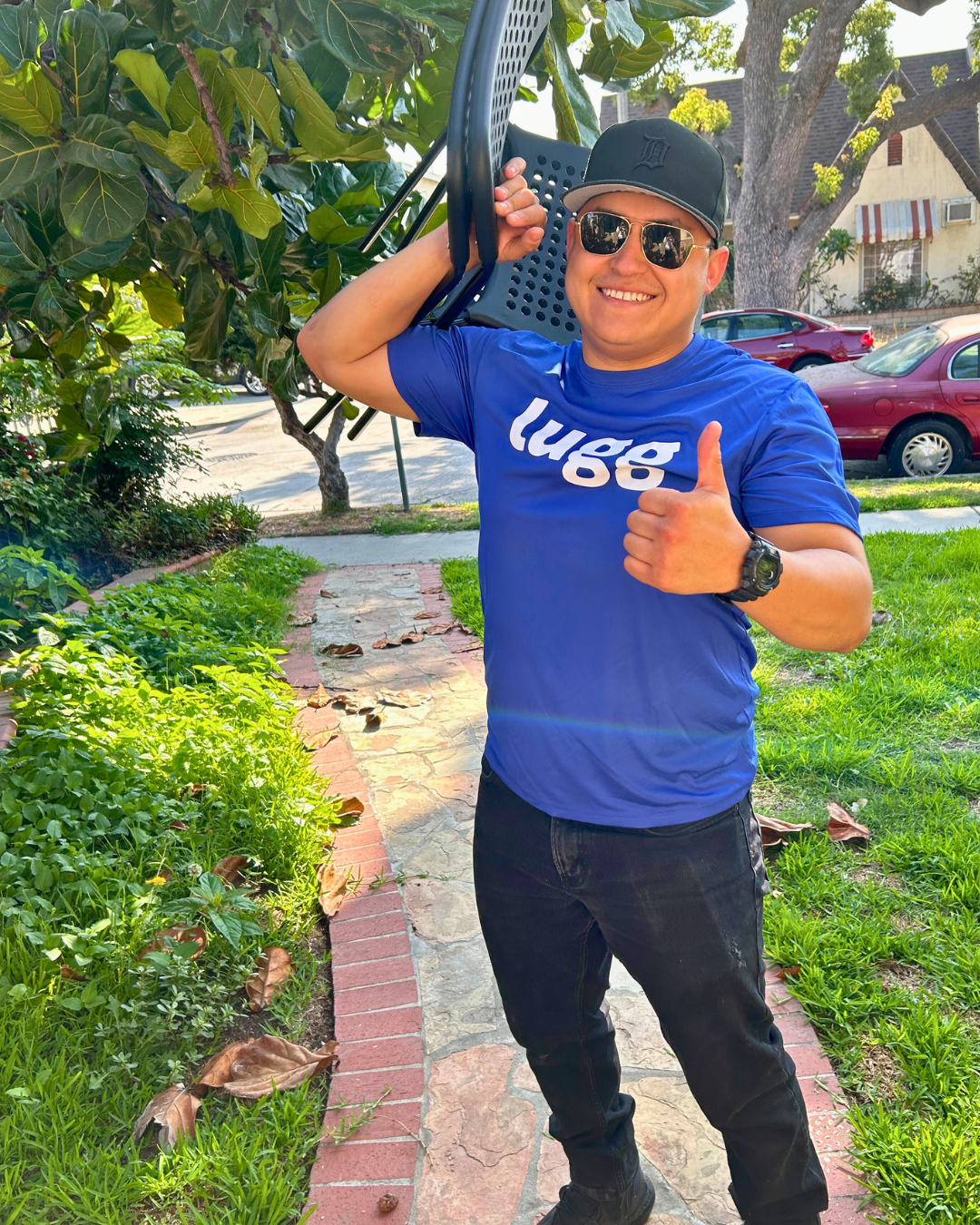 Lugg Helper outdoors, giving a thumbs up while carrying a chair, showing confidence and readiness.