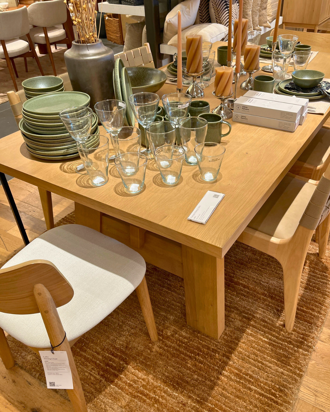 West Elm showroom with a large wood dining table, glassware, plates, and décor available for same-day delivery.
