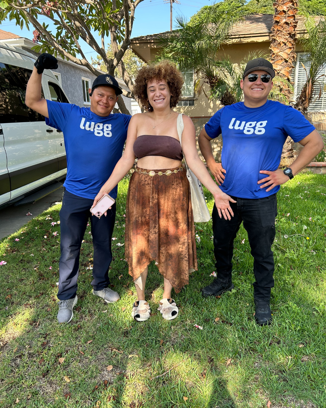 Two Lugg movers smile and pose outside with a happy customer in front of a van.