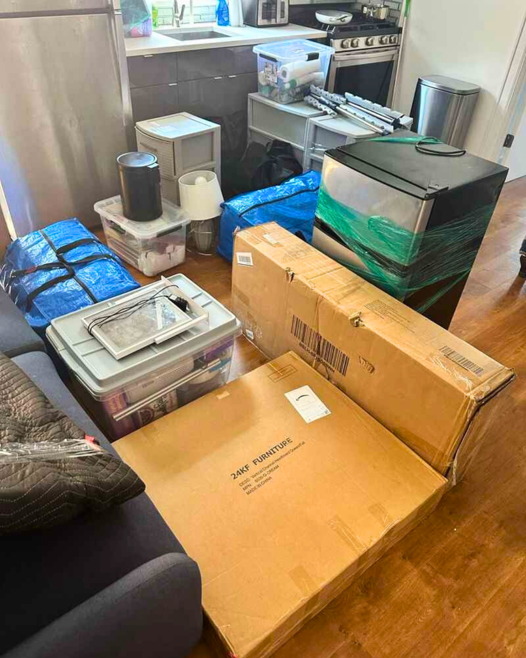 Boxes, mini fridge, and furniture inside a dorm kitchen area during move-in day.
