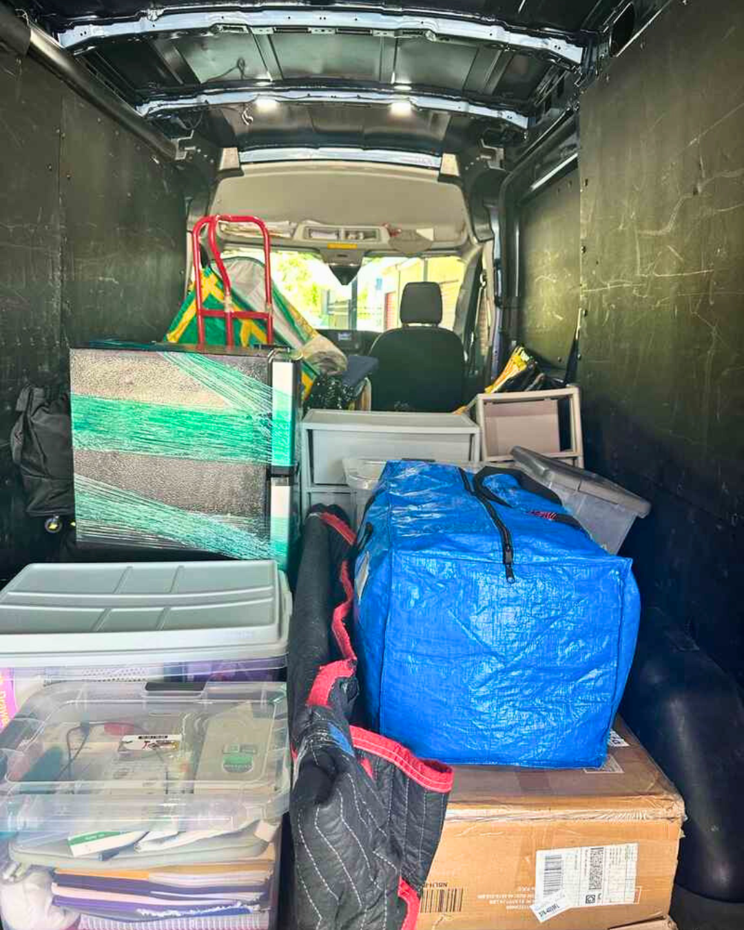 College move-in items including bins, boxes, and furniture packed in a moving van.