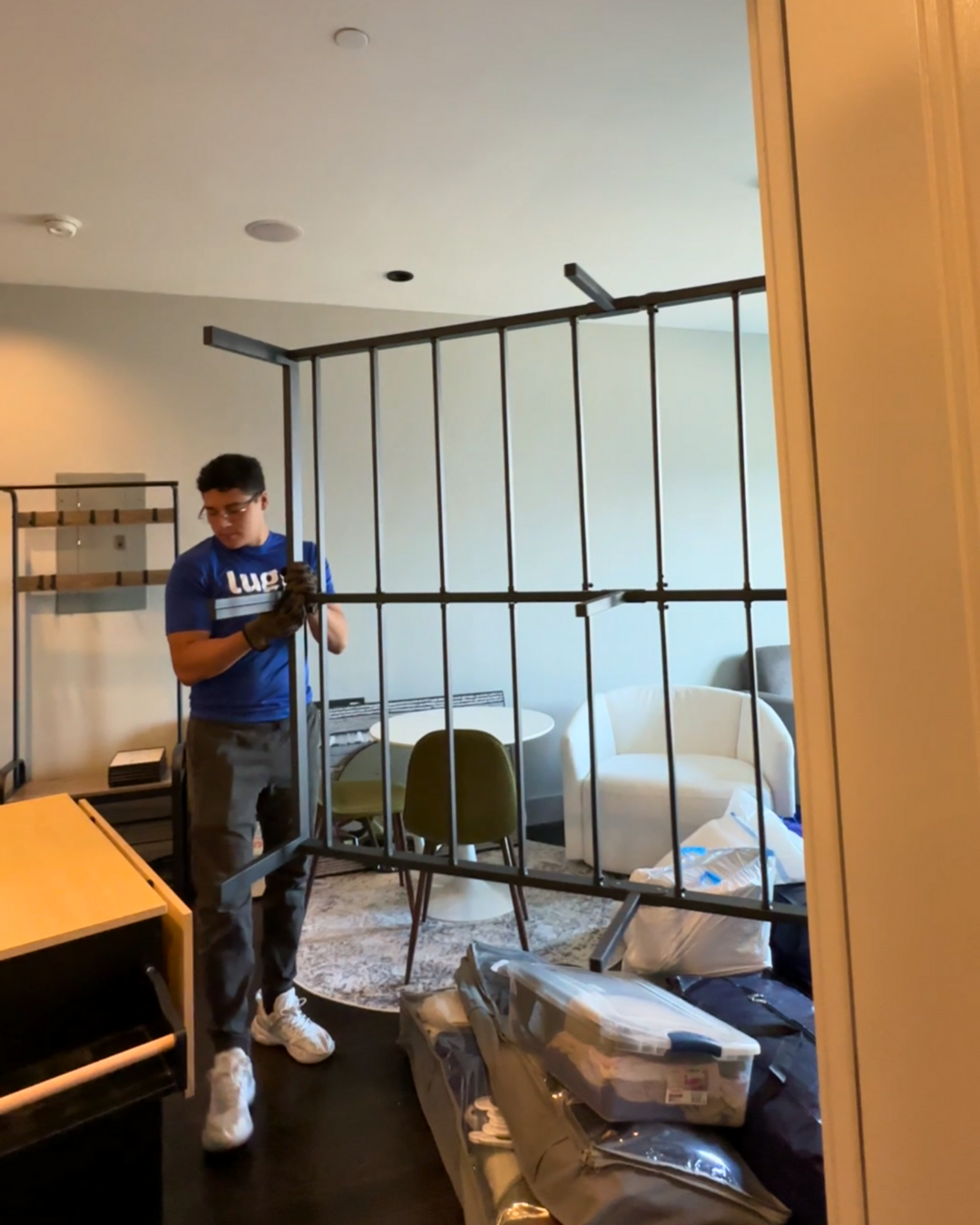 A Lugg mover carrying a metal dorm bed frame inside a college room.