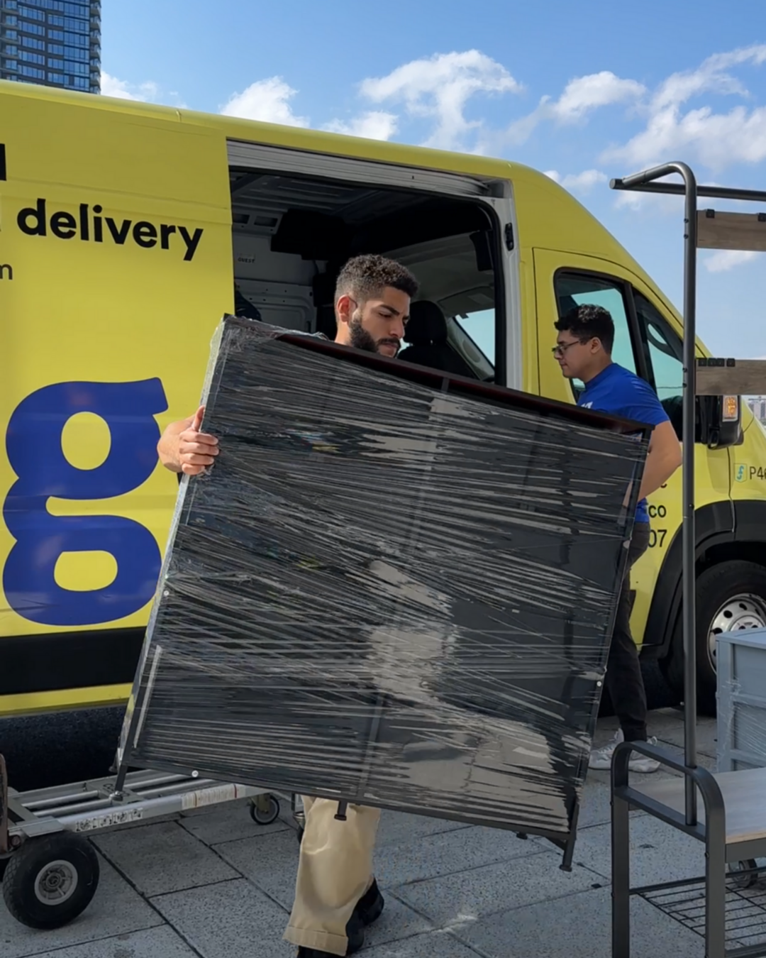 Lugg mover unloading a wrapped furniture piece from a branded yellow truck, emphasizing quick and professional moving service.