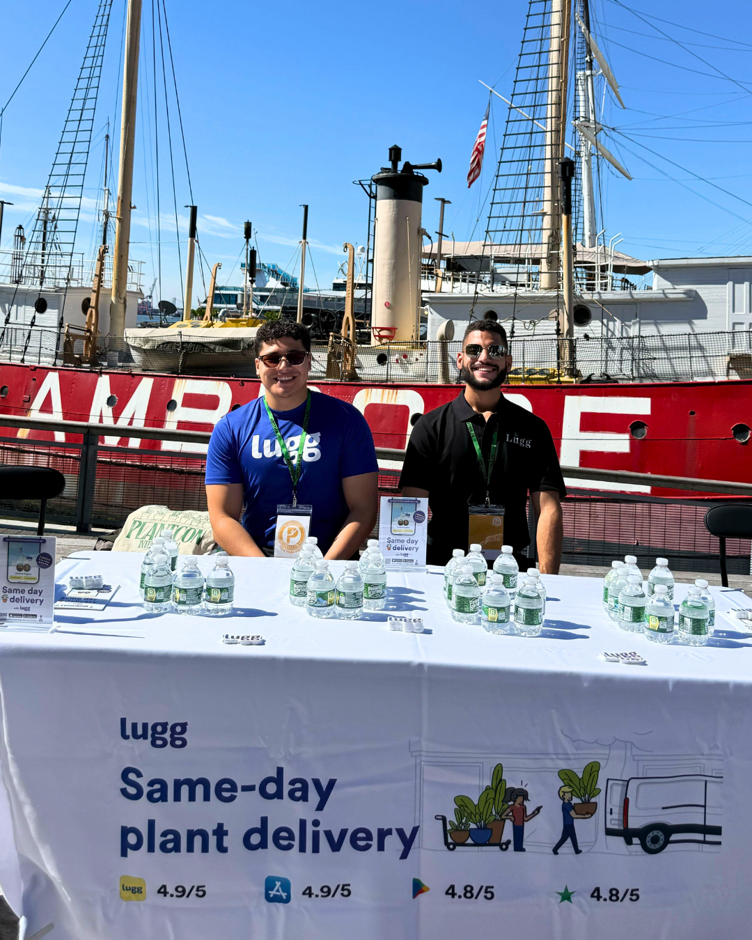 Derek and Luis representing Lugg at a PlantCon NYC booth with a branded tablecloth and water bottles.