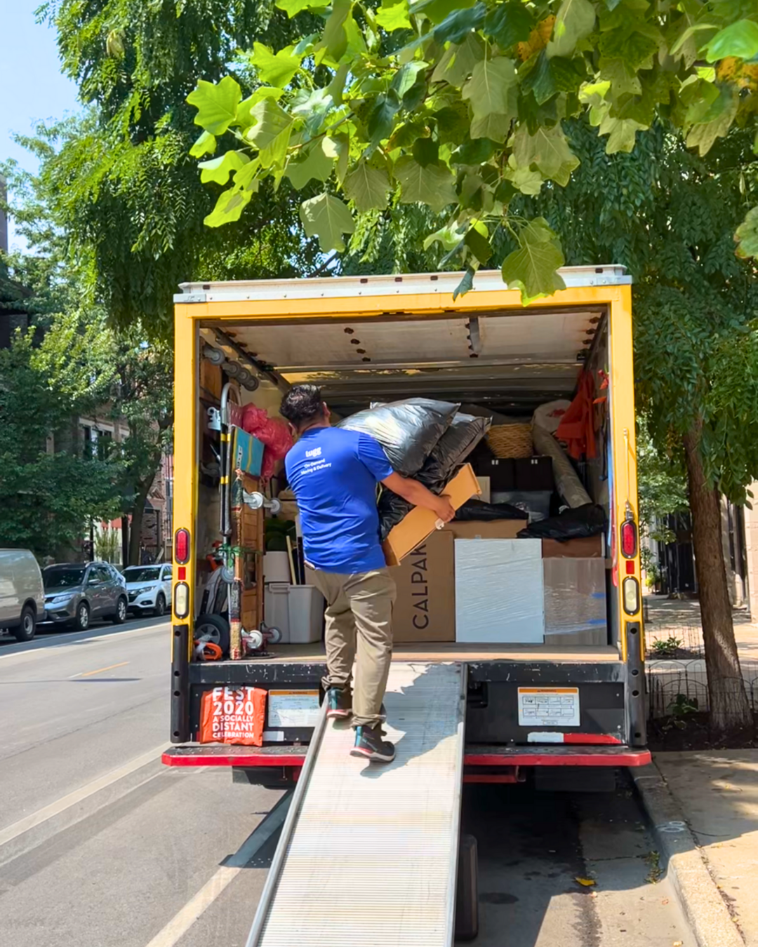 Lugg mover carrying bags up a ramp into a packed moving truck.