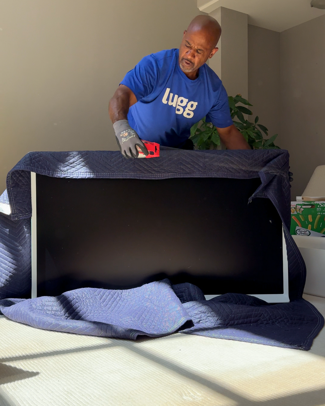 Lugg mover wrapping part of a couch in a moving blanket for protection.
