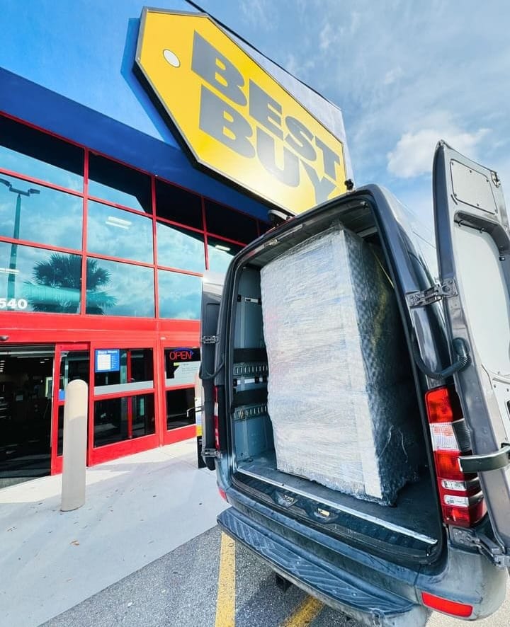 A new Best Buy refrigerator secure wrapped and loaded into a moving van.