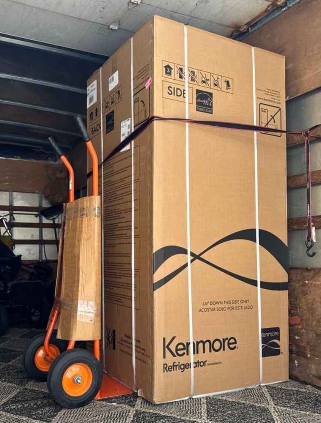 Large boxed Kenmore refrigerator secured inside a Lugg Box truck with a hand truck, demonstrating appliance moving capability.