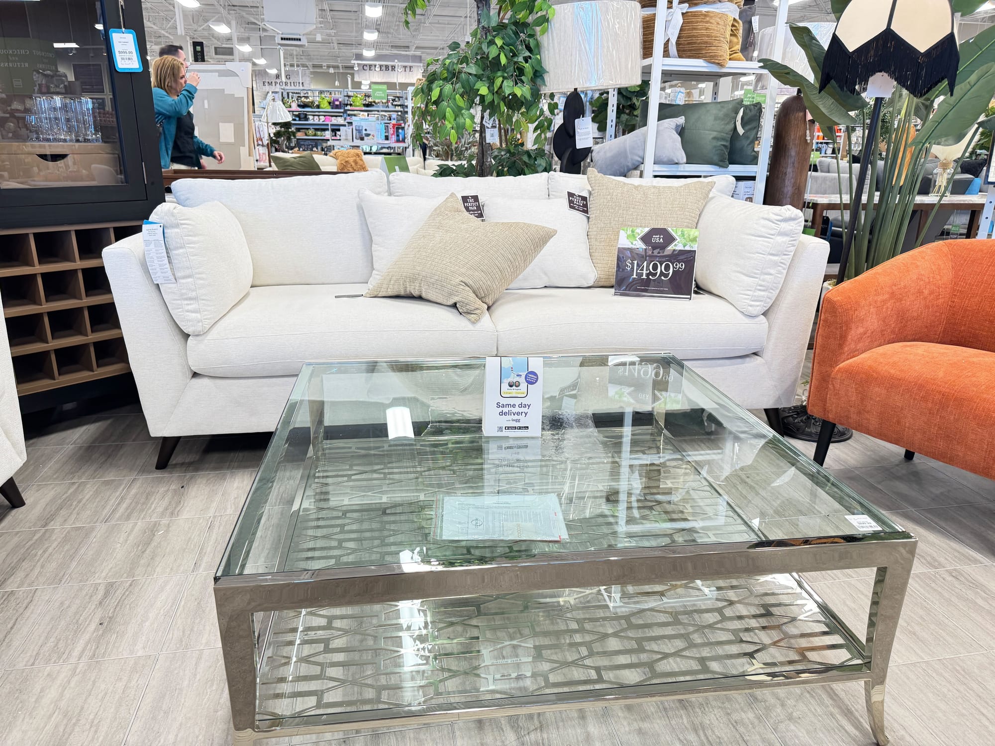 White sofa with $1,499.99 price tag and Lugg same-day delivery card in a furniture showroom