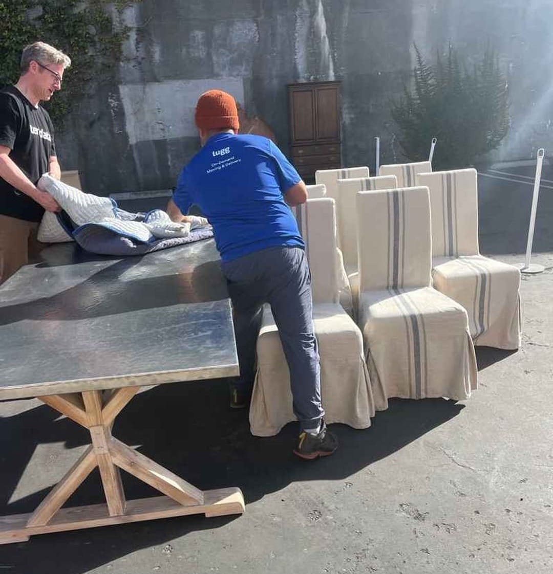 Lugg movers wrapping a dining table and chairs for delivery from a furniture outlet