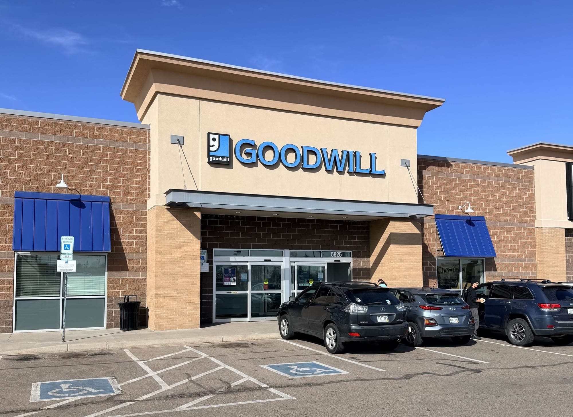 Goodwill donation center storefront with blue awnings and parking lot on a clear day