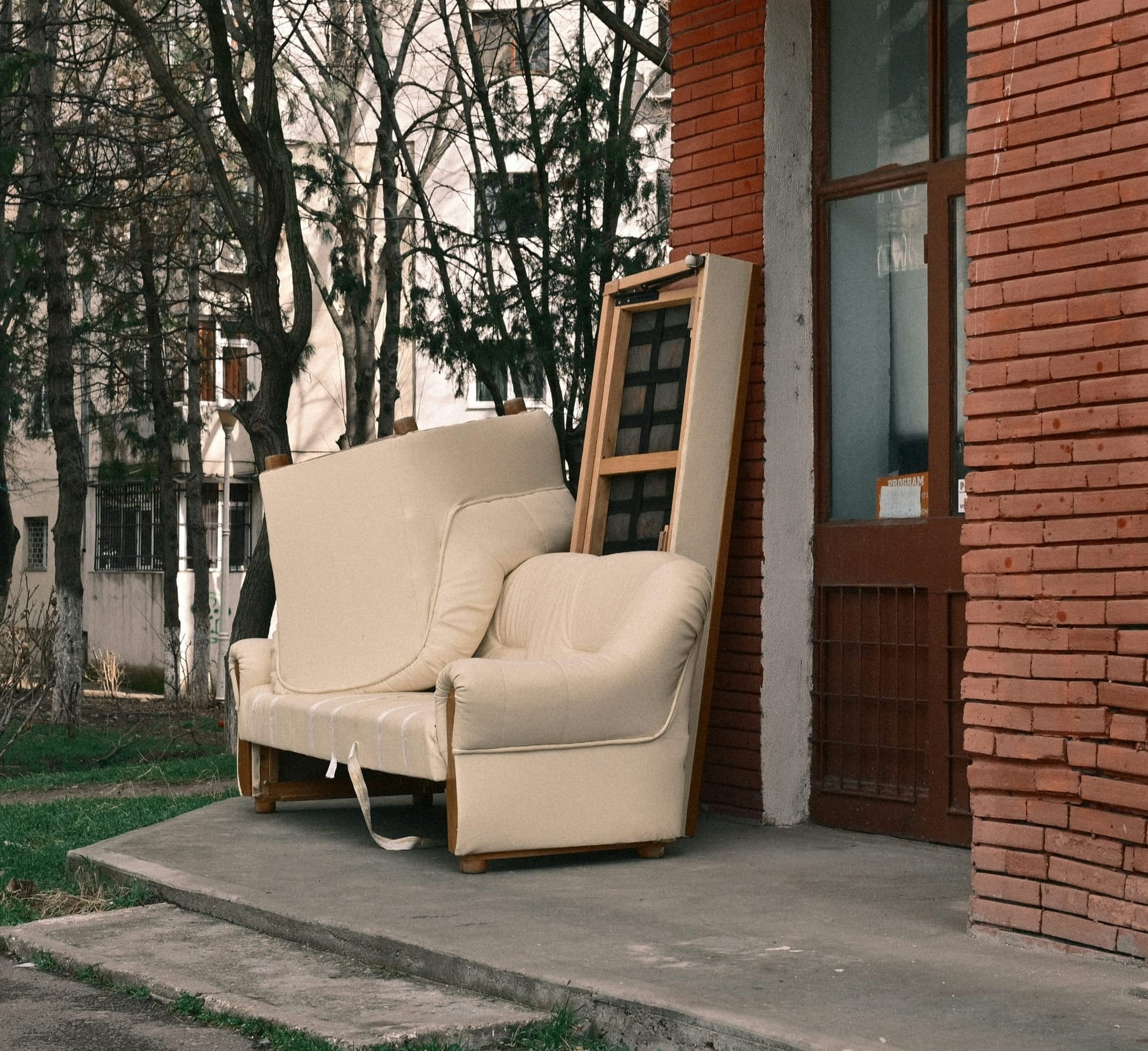 A cream sofa and framed mirror left at the curb — the fate of furniture not donated or sold before a move