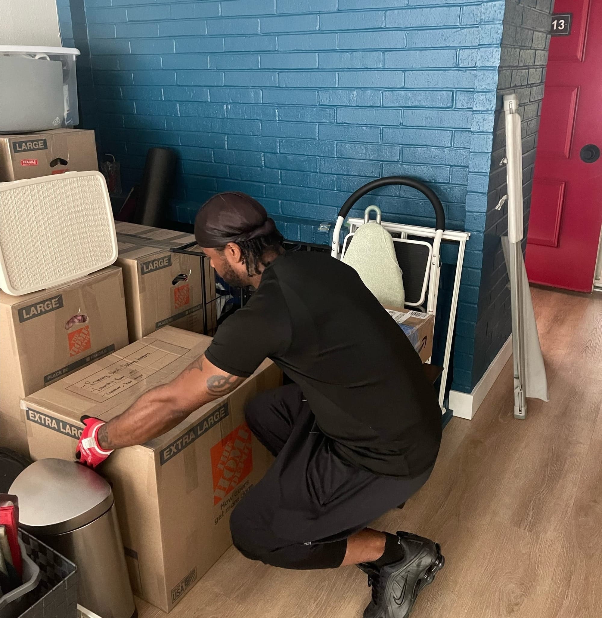 Robert W., a Lugg helper in Seattle, kneels in gloves to get a grip on an extra-large moving box during a job.