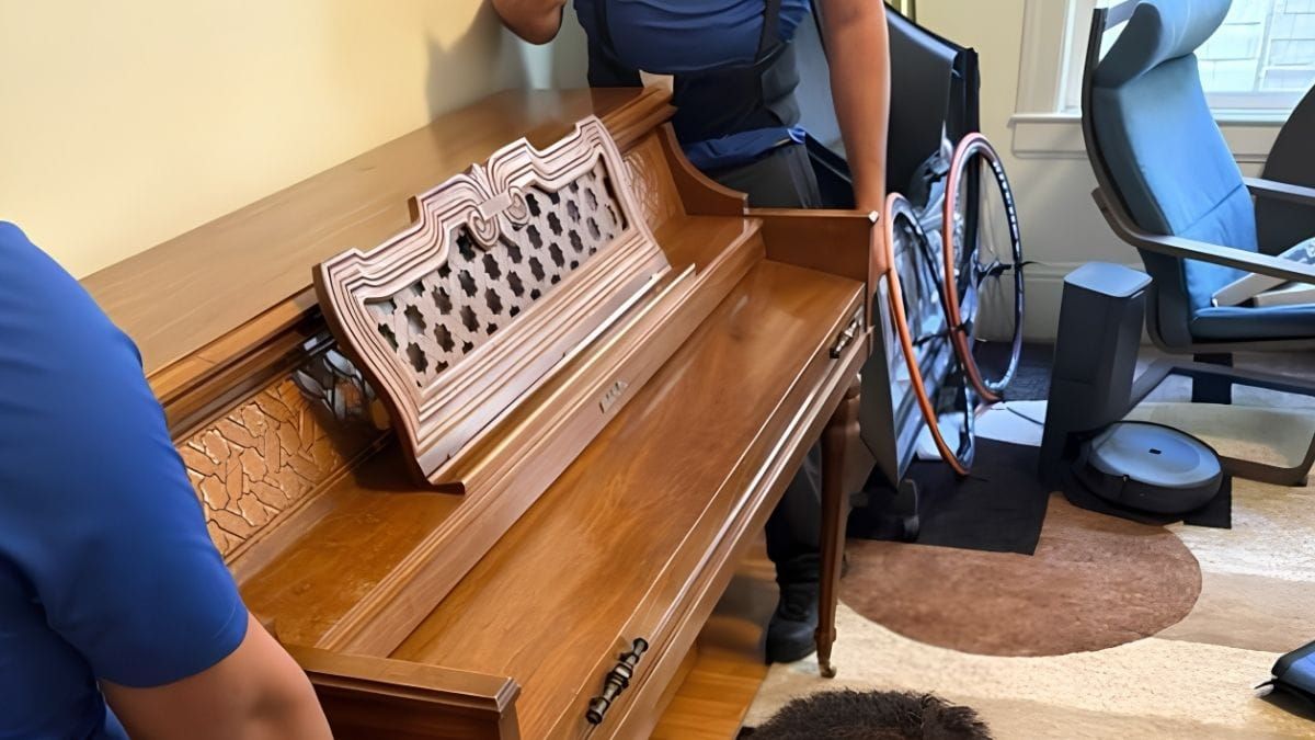Two Lugg movers carefully positioning a wood upright piano in a customer's living room during a residential piano move.
