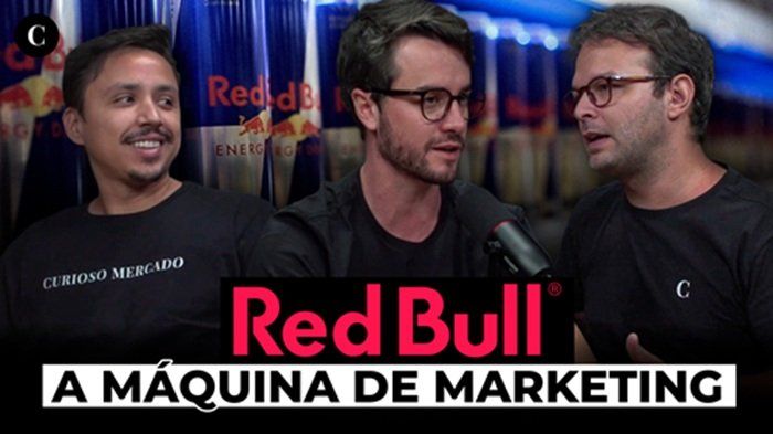 Imagem mostra os criadores do Curioso Mercado conversando ao redor de uma mesa, no lançamento do seu podcast. Sobre a imagem