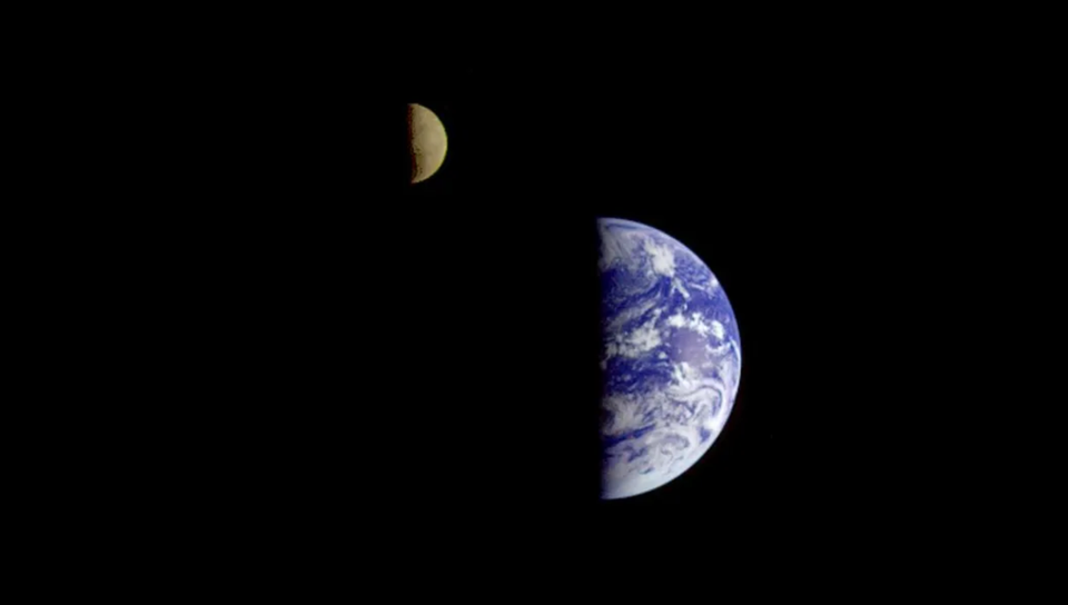Image taken by the Galileo spacecraft showing both the Earth and the Moon in quarter phase, with the sun angle from the right, on the black background of space.