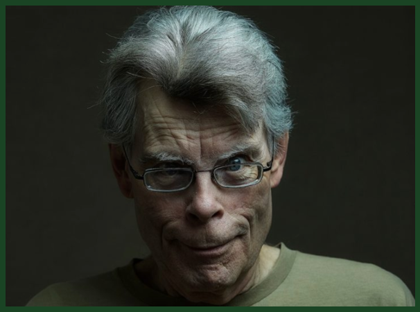 Head shot photo of an older white man with short grey hair and a muted green tshirt wearing glasses with a disturbing smile.