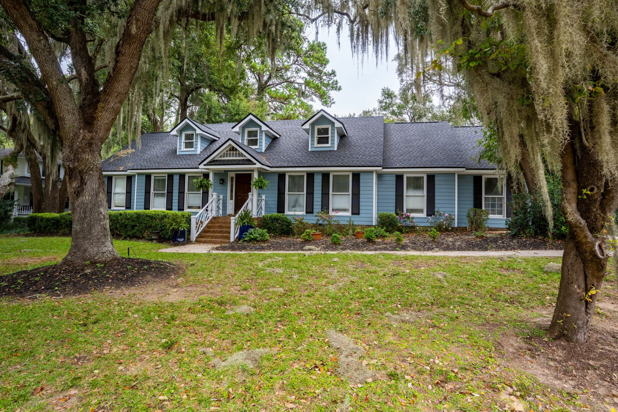 Spanish moss frames a two-story ocean blue rental property in South Carolina.
