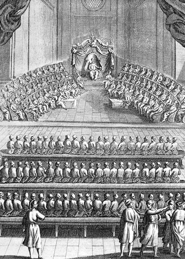 A black and white image with a dude at the front and a lot of dudes sitting in semicircircle around him, and then a bunch of benches facing the semicircle, full of dudes A black and white image with a dude at the front and a lot of dudes sitting in semicircircle around him, and then a bunch of benches facing the semicircle, full of dudes