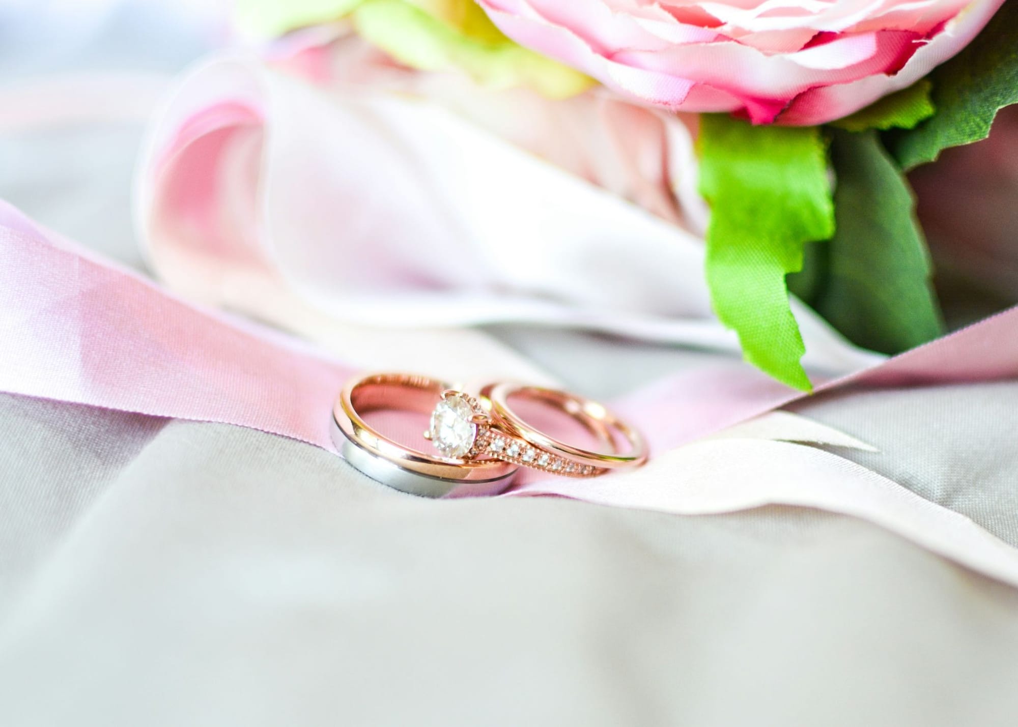 ピンクのリボンの上に置かれた結婚指輪