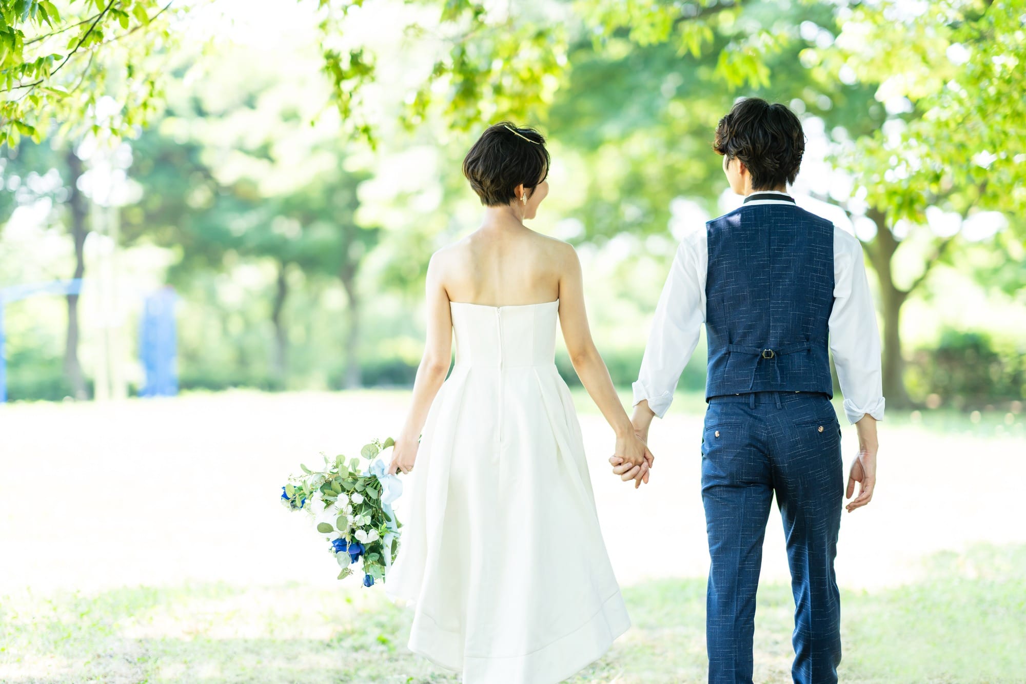 手をつないで歩く新郎新婦の後ろ姿