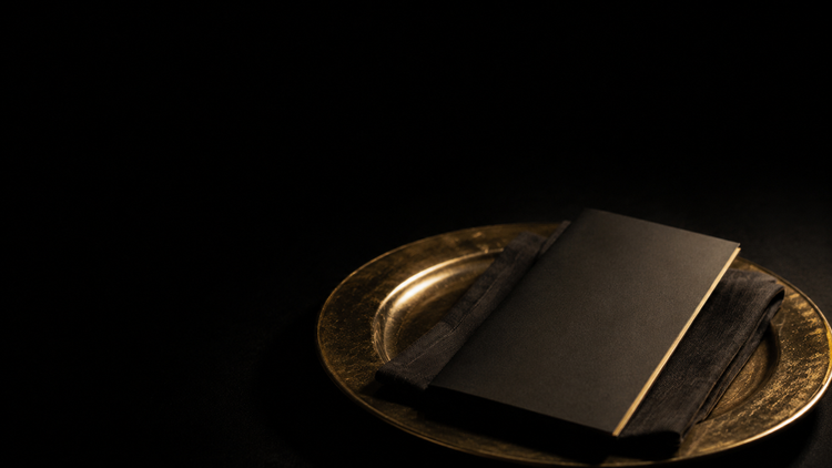 A blank closed menu on a gold-rimmed place setting — Order First, a Golden Scalpel Resident Corner guide to physician practice models.