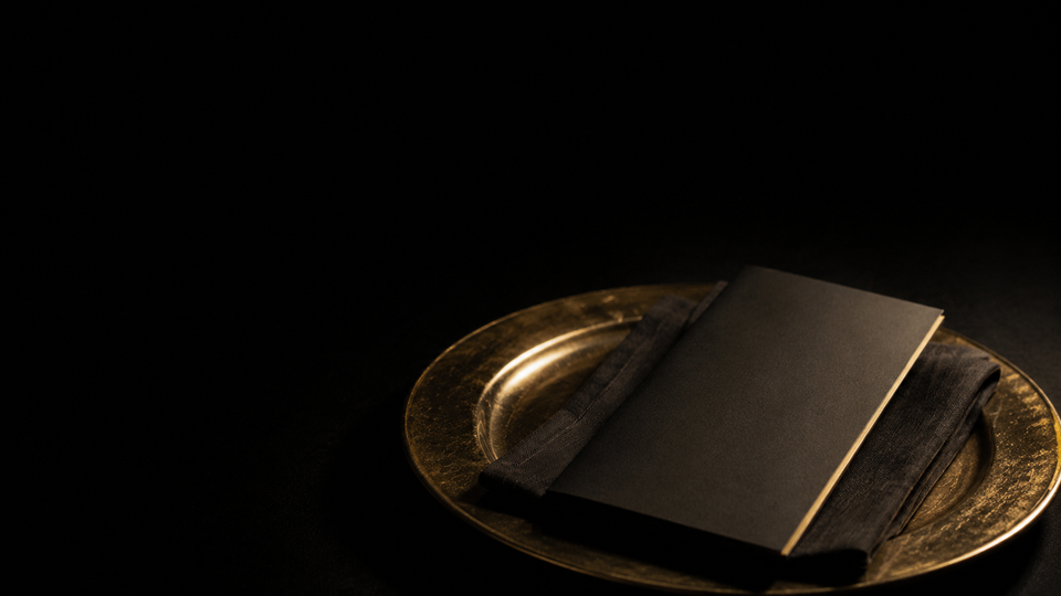 A blank closed menu on a gold-rimmed place setting — Order First, a Golden Scalpel Resident Corner guide to physician practice models.