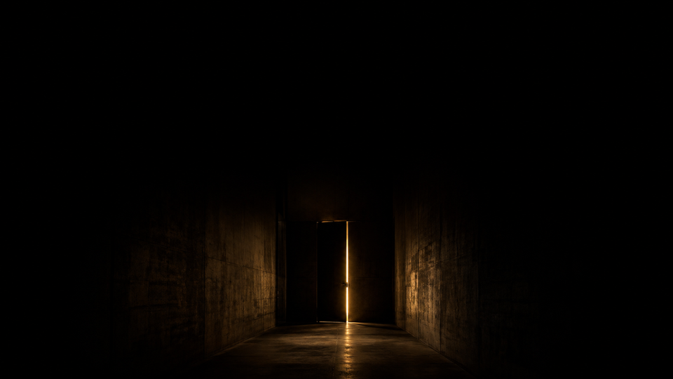 A dark corridor with a sliver of warm gold light from a door ajar — Before You Say No to Rural, a Golden Scalpel Resident Corner guide.