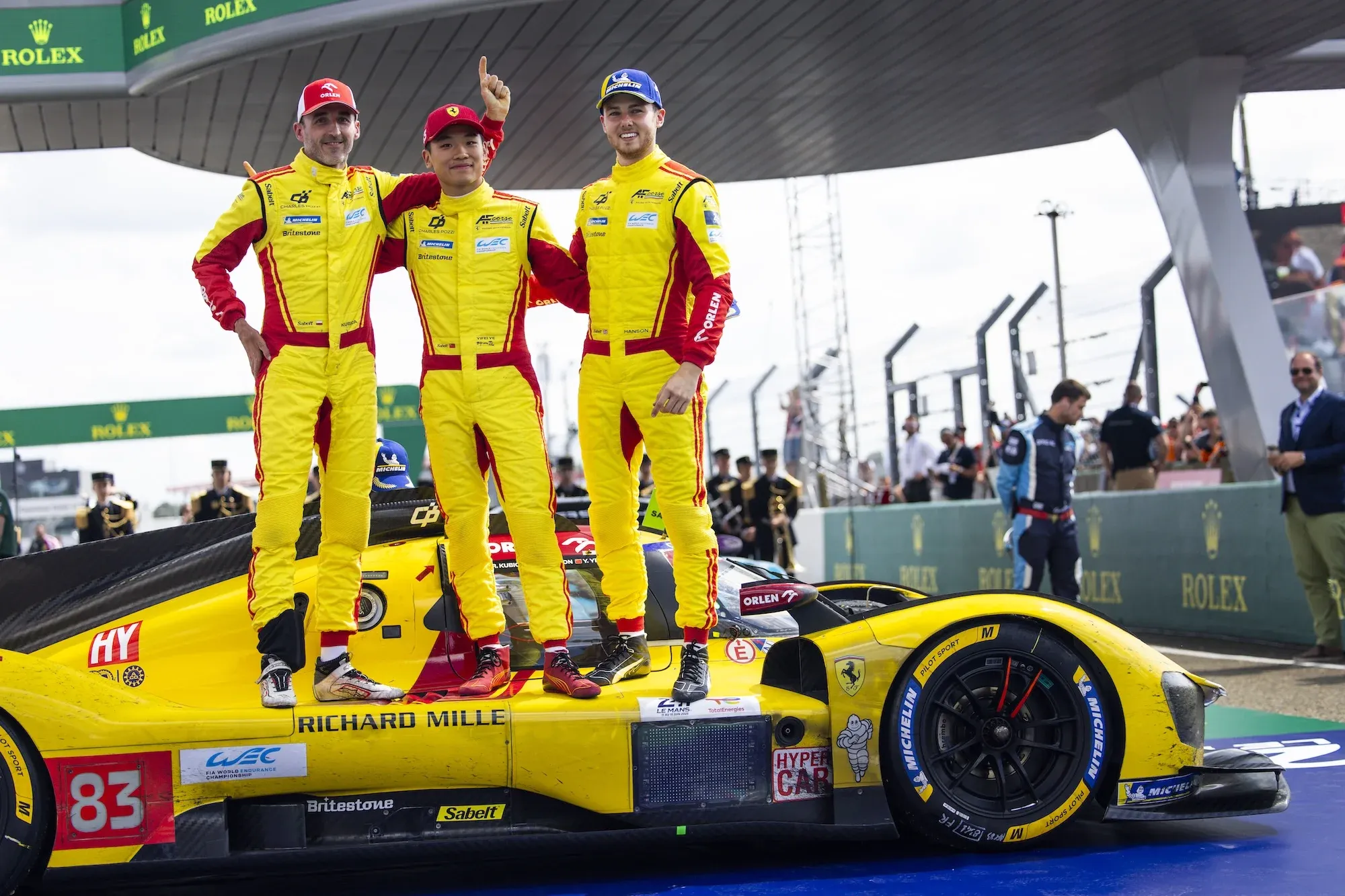 Robert Kubica, Yifei Ye, and Phil Hanson celebrating after the race, standing on their car below the podium