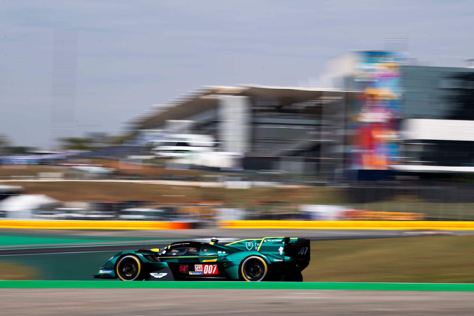 The #007 Aston Martin at Interlagos, with the paddock building in the background