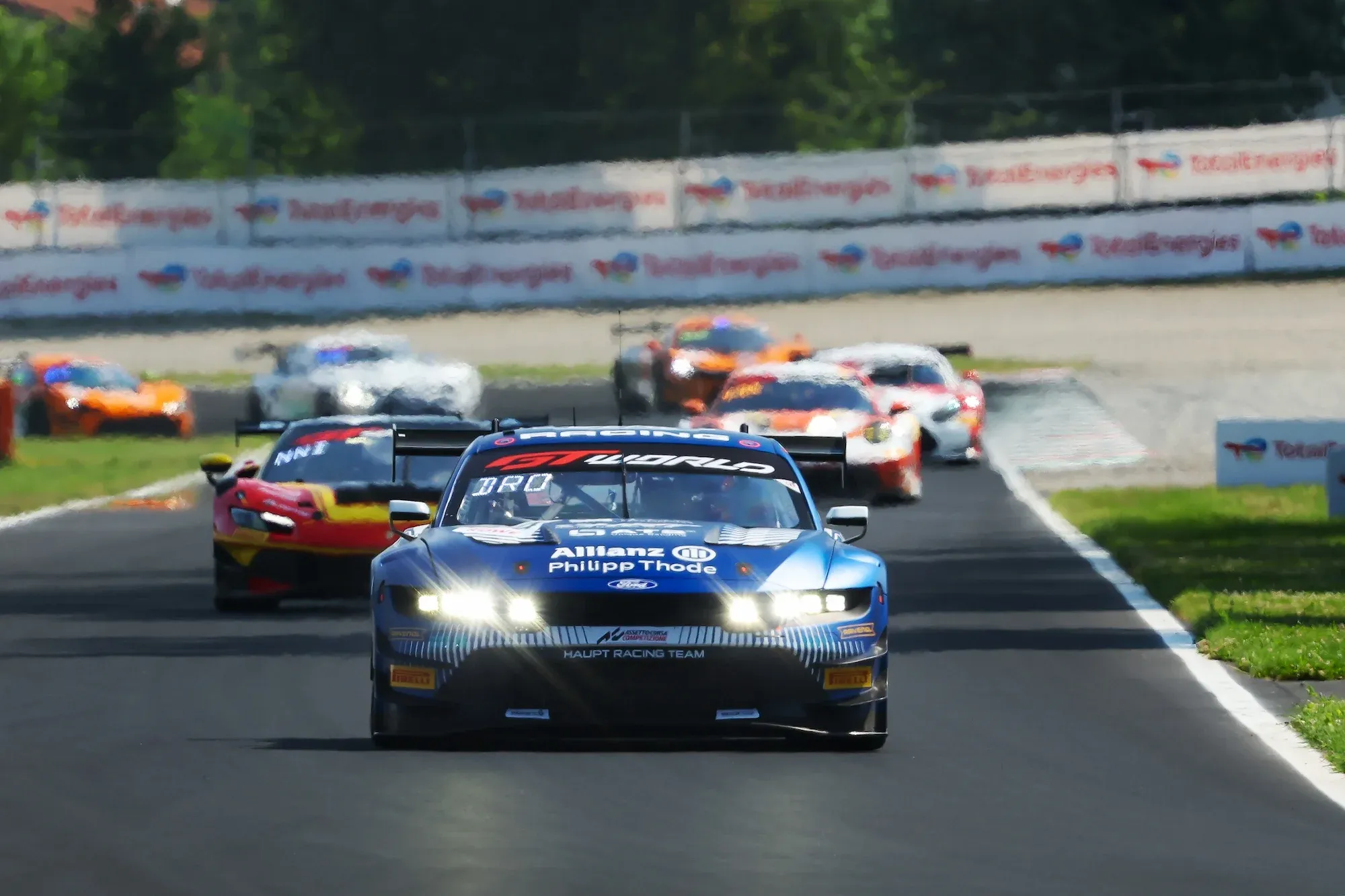 A Ford Mustang leads a Ferrari 296 and other cars at Monza