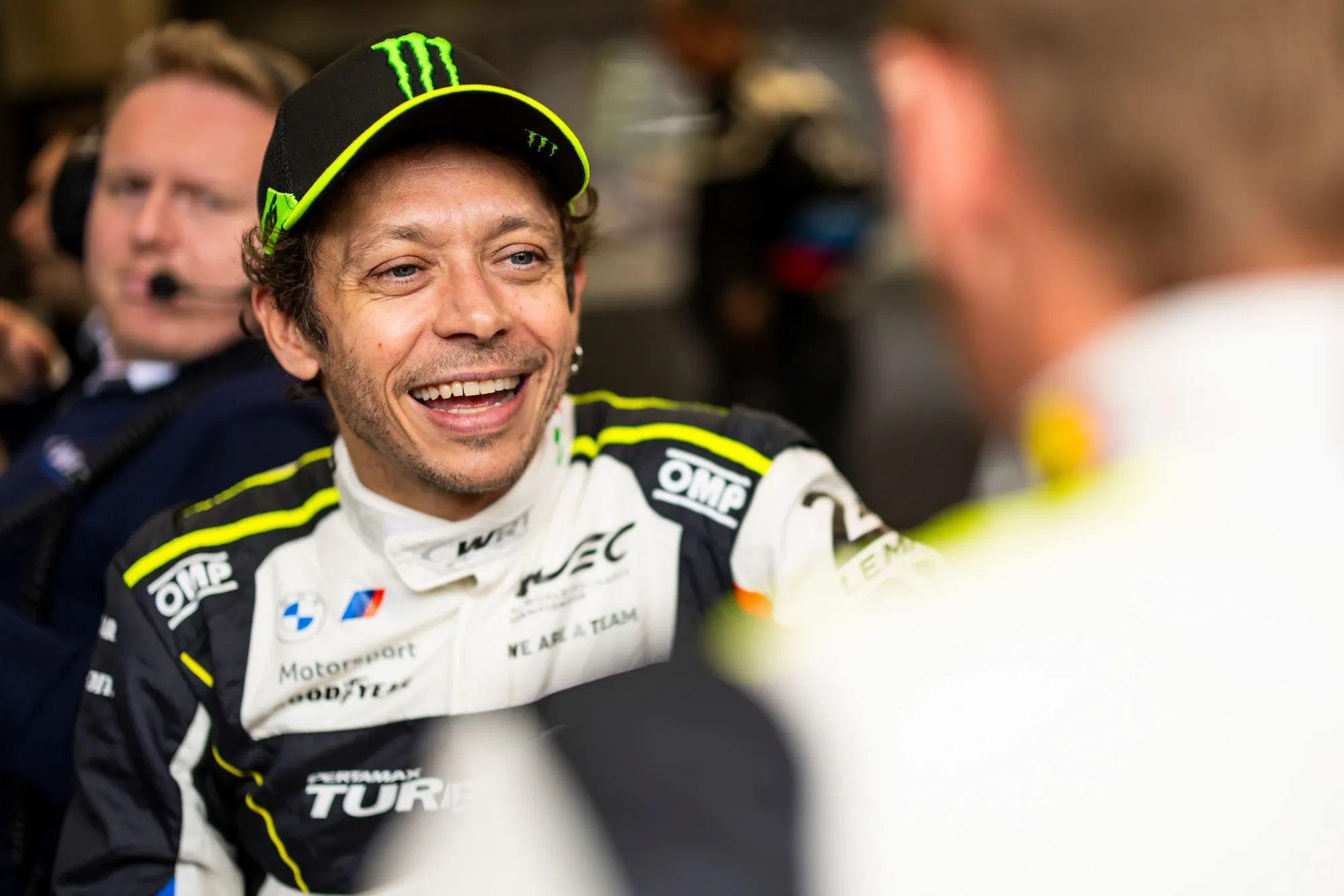 A picture of Valentino Rossi smiling while wearing his racing overalls and a baseball cap. Photo Julien Delfosse / DPPI