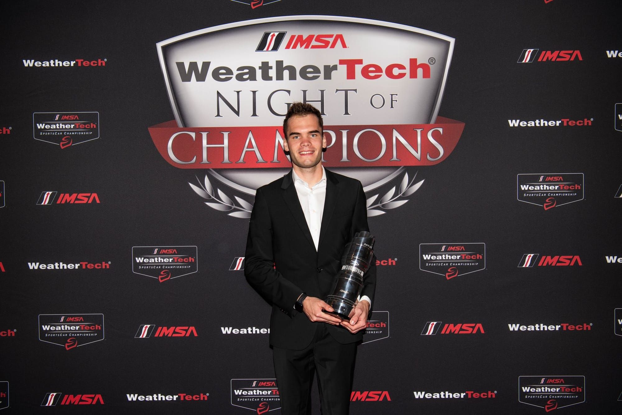 AO Racing's Lauren Heinrich at last year's IMSA awards ceremony, in a suit holding a trophy