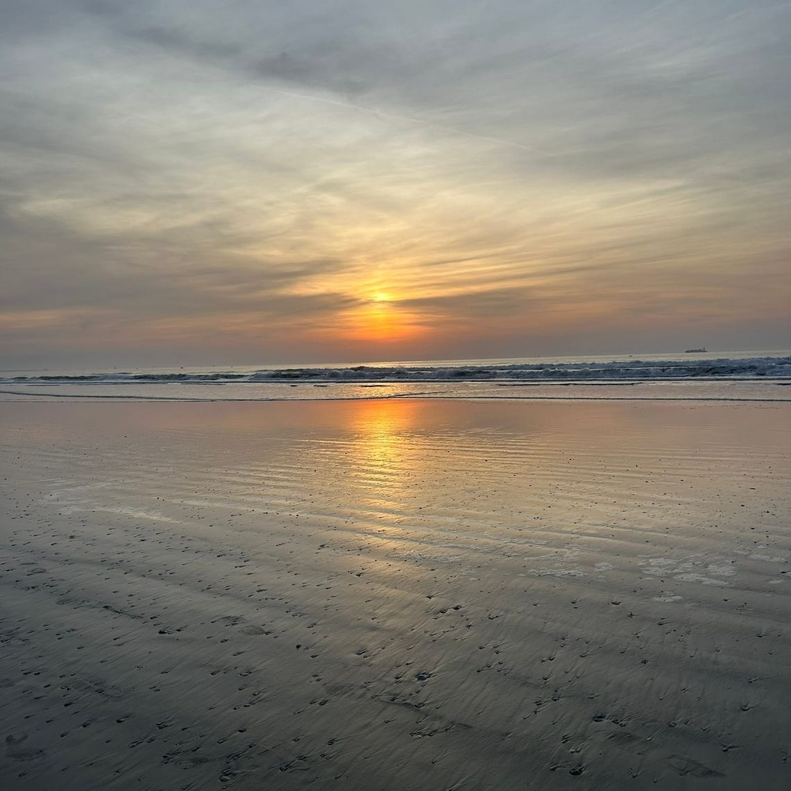 A sunrise on the ocean with orange, blue, and gray tones