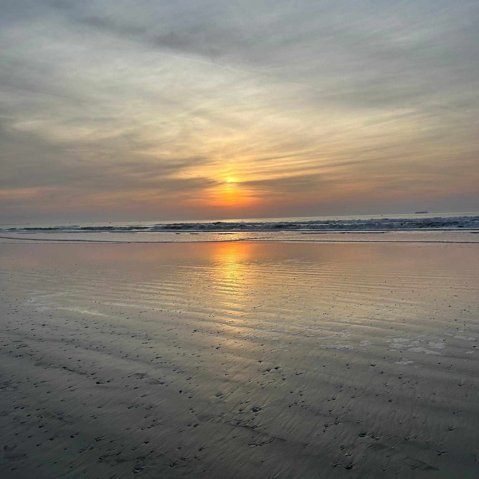 A sunrise on the ocean with orange, blue, and gray tones