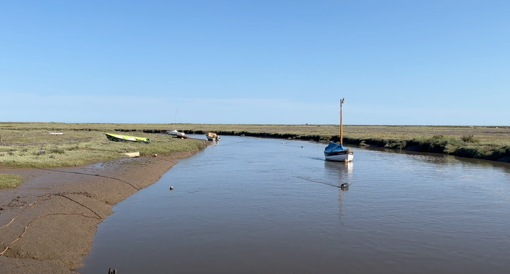 moored boat in an estuary with tidal salt marsh in the background