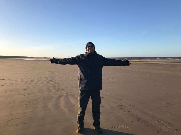 a man on a beach with his arms stretched out