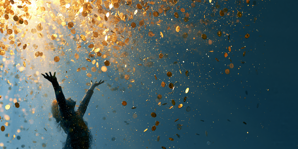 A silhouette of a person reaching up toward a cascade of gold coins falling from above, against a deep blue background.