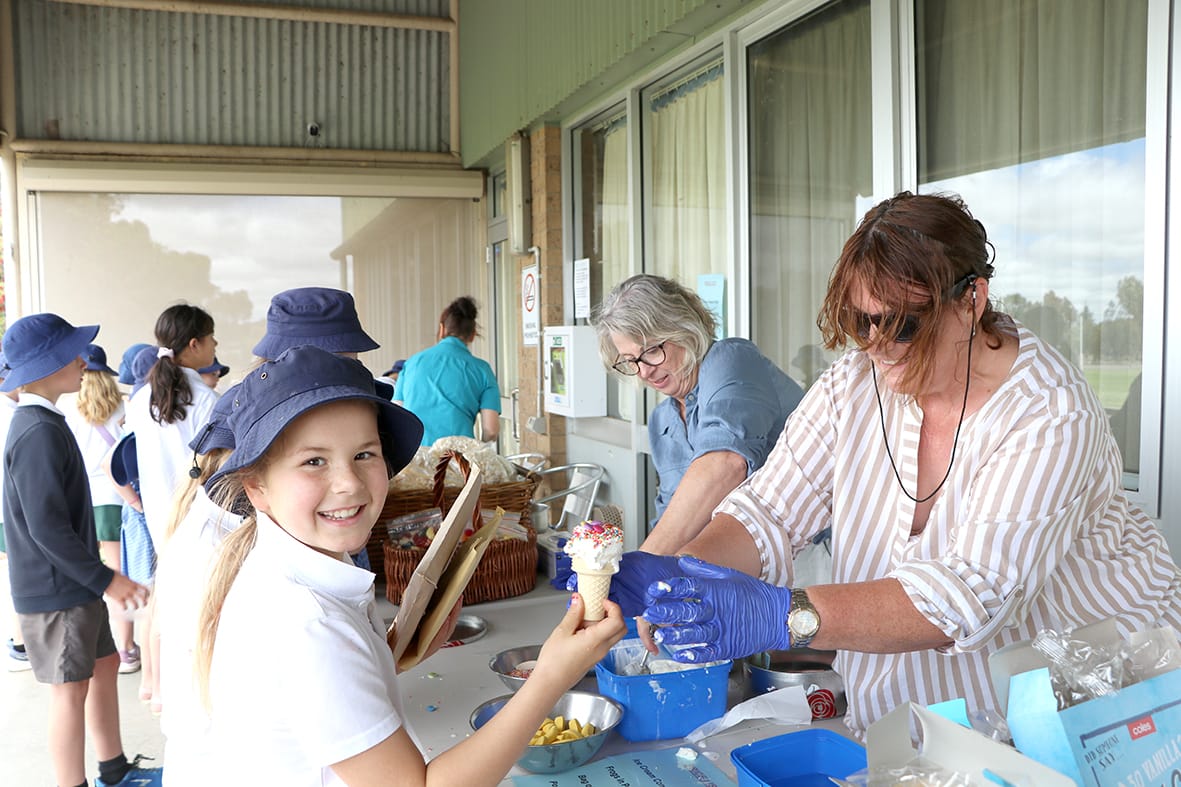 EWHS staff Julie Lowry and Jenny Noonan in the blustery conditions serving ice cream to Ari Richmond.