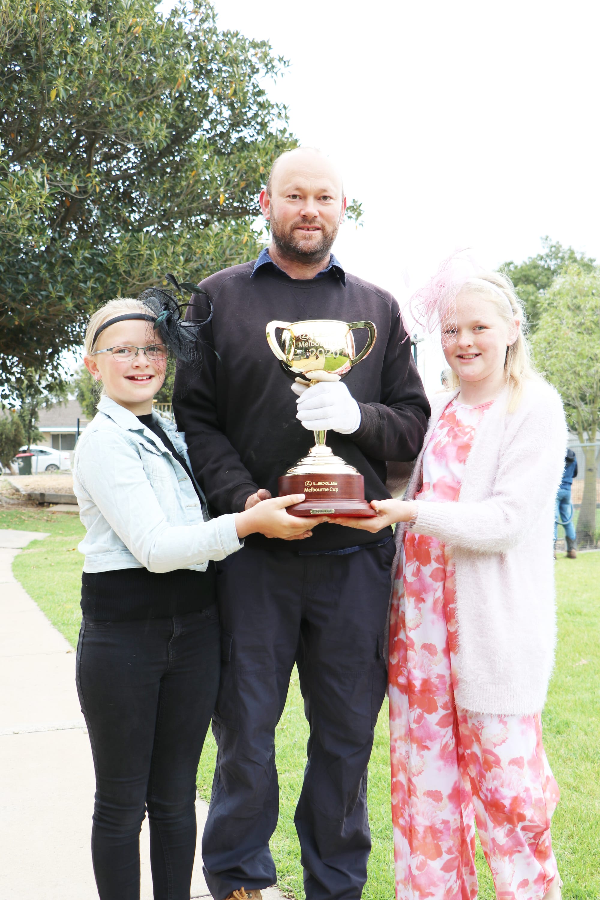 Holding the Melbourne Cup, Lana (left), Darren and Zali Angel.