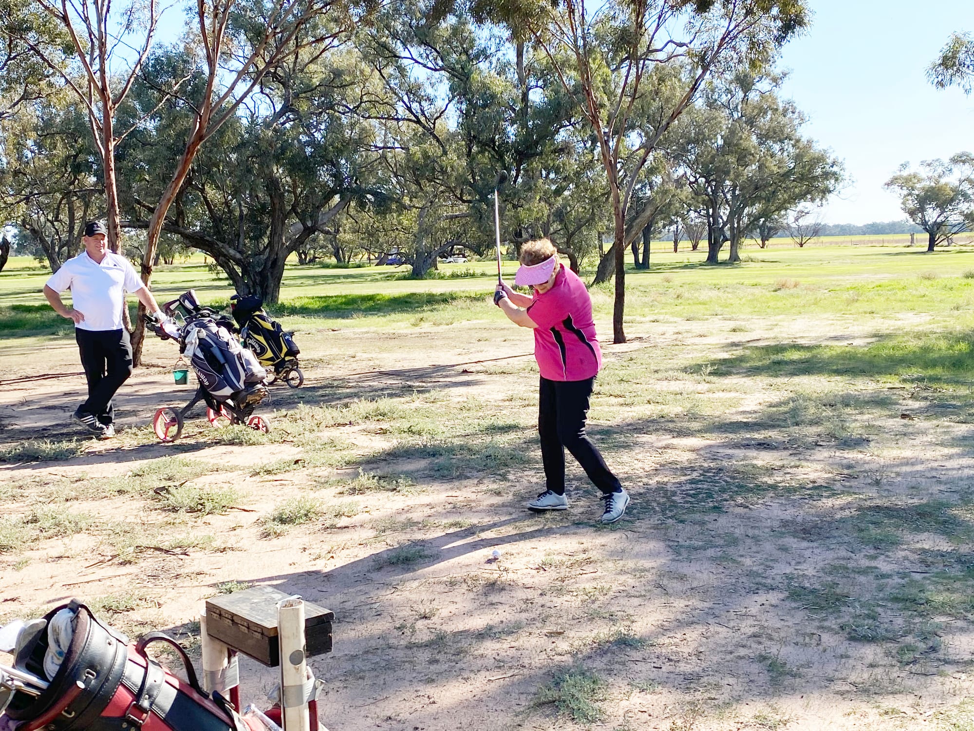 With club president, Brad Ryan, looking on, Peg Hogan hits during the weekend’s round of golf at Birchip.