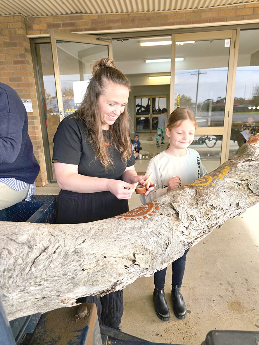 Artist Kristie Witt working with Addison on their log painting.