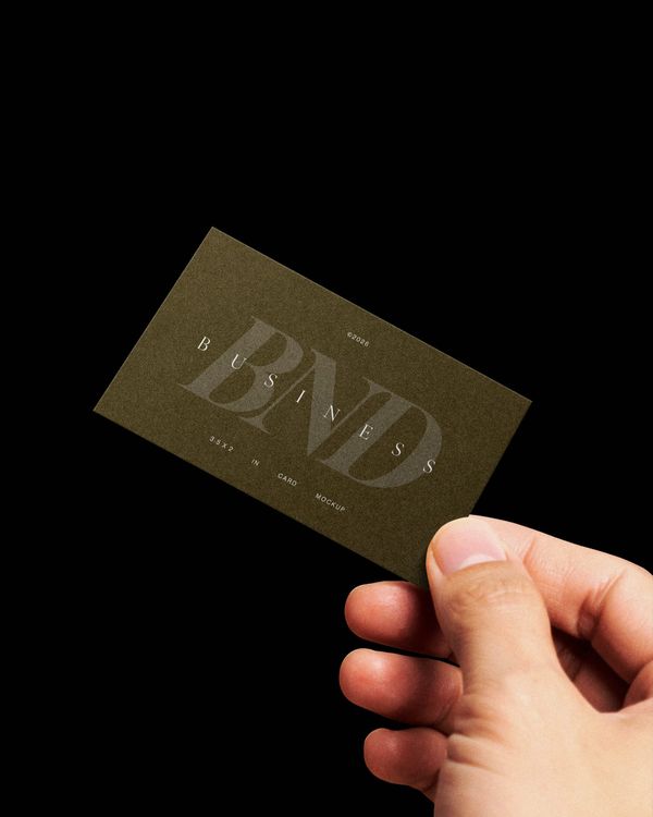 hand holding business card mockup on dark background with minimal lighting