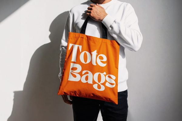 Hand Held Tote Bag Mockup with Sunlight on White Wall