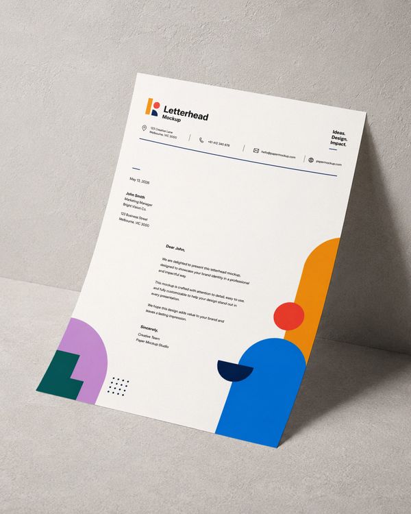Angled letterhead mockup standing against a textured wall with colorful geometric branding and soft natural shadows.
