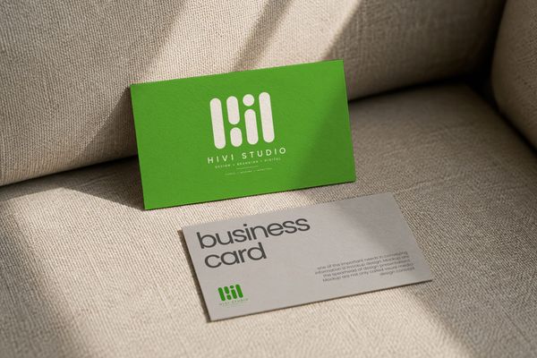 Business card mockup displayed on a textured fabric surface with warm natural lighting.