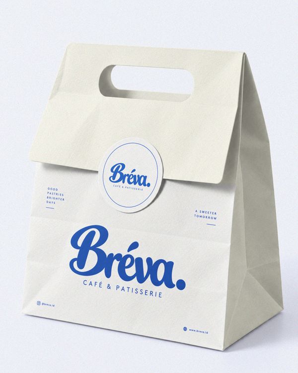 Sticker and folded bakery bag mockup featuring a premium white paper bag, a circular branded sticker, and elegant blue typography, presented on a clean studio background.
